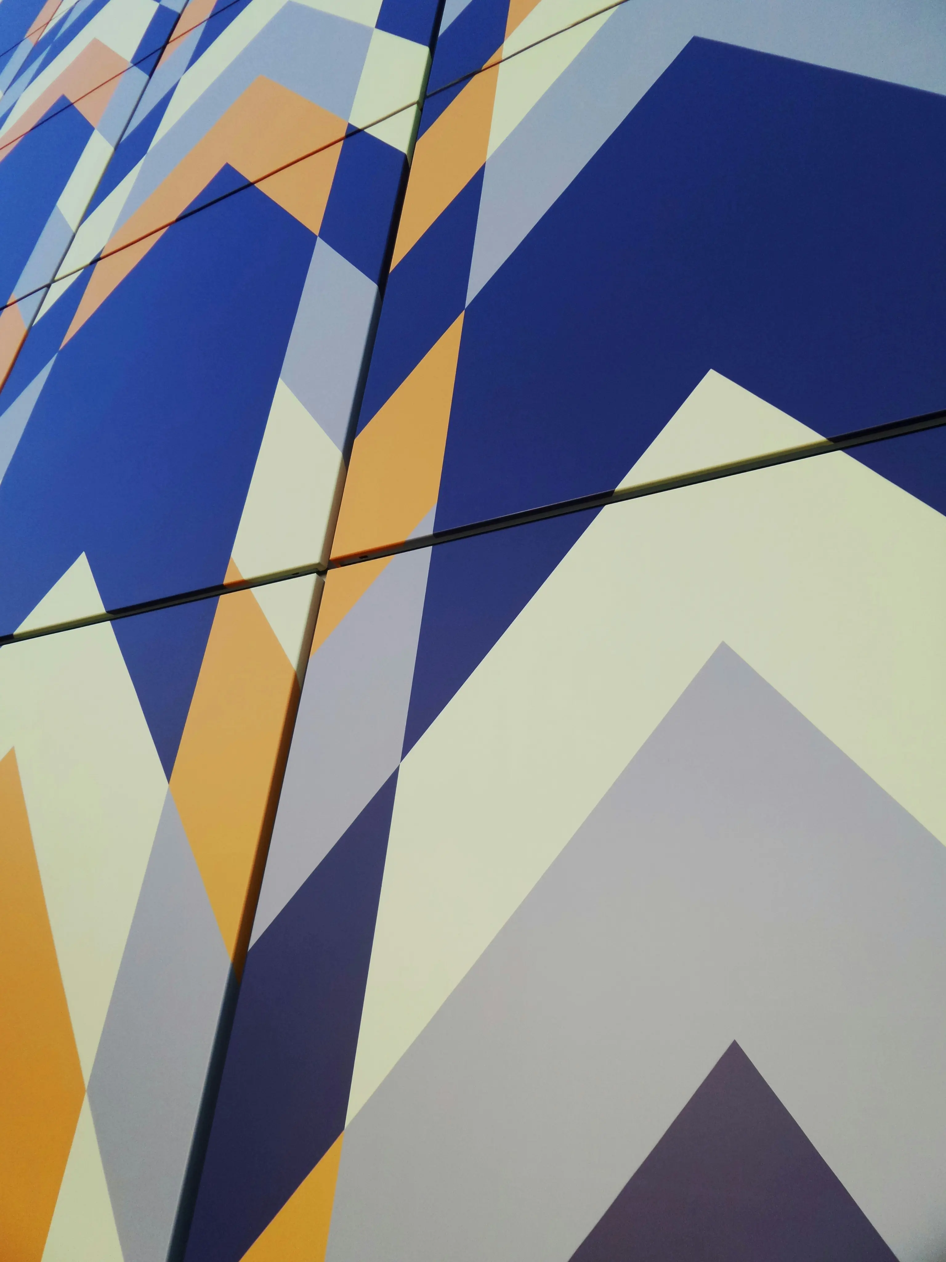 Fresque murale géométrique bleu, orange et blanc évoquant des montagnes
